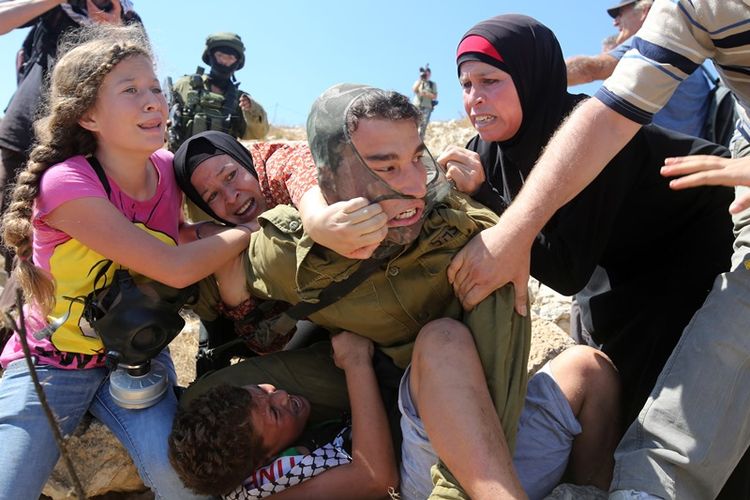 Ahed Tamimi (kiri) ketika bersitegang dengan seorang pasukan Israel. Tamimi dan keluarganya ditangkap militer setelah beredar video dirinya menampar serdadu Israel yang berjaga di Tepi Barat.