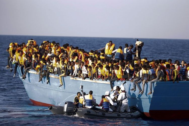 Foto ini diambil pada 29 Agustus 2016 menunjukkan petugas penyelamat Italia mengevakuasi seorang perempuan yang berada di sebuah kapal dengan ratusan imigran lainnya. (Associated Press)