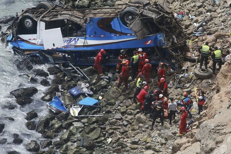 Petugas pemadam kebakaran mengangkat tubuh korban dari sebuah bus yang jatuh dari tebing setelah ditabrak oleh truk trailer, di Pasamayo, Peru, Selasa (3/1/2018). (Kantor Berita Andina via AP)