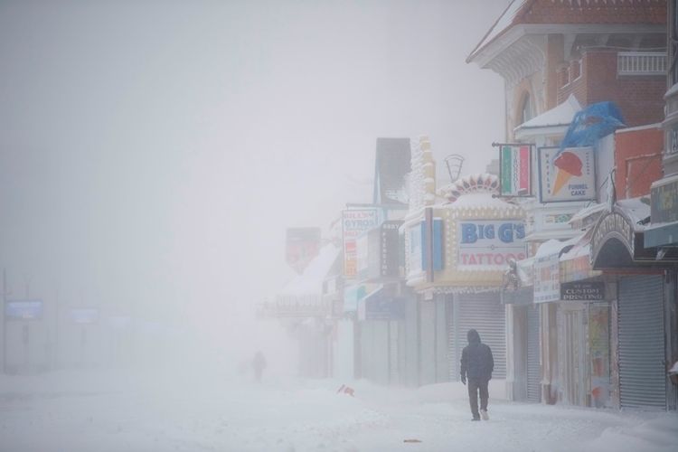 Seorang pria berjalan di atas papan kayu yang tertutup salju saat badai salju pada Kamis (4/1/2018), di Atlantic City, New Jersey. (AFP/Mark Makela)