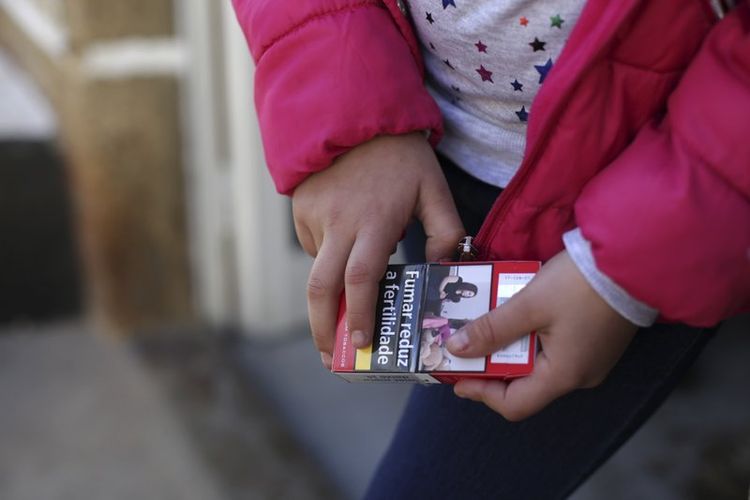 Natasha (8) memegang sebungkus rokok di desa Vale de Salgueiro, utara Portugal, pada perayaan Epifani, Sabtu (6/1/2018). (AP Photo/Armando Franca)