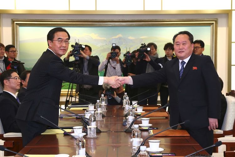 Menteri Unifikasi Korea Selatan Cho Myung Gyun (kiri) berjabat tangan dengan pemimpin delegasi Korea Utara Ri Son Gwon (kanan) dalam pertemuan resmi di Panmunjom, di Zona Demiliterisasi, Selasa (9/1/2018). (AFP/Dong A Ilbo) 