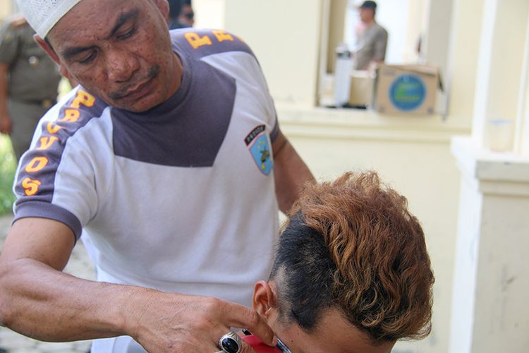 Petugas Satpol PP sedang mencukur rambut anak punk yang terjaring dalam razia syariat islam, sembilan anak punk dan 4 LGBT setelah rambutnya dicukur akan menjalani pembinaan ilmu agama di rumah singgah Dinas sosial Kota Banda Aceh, Selasa (9/1/18).