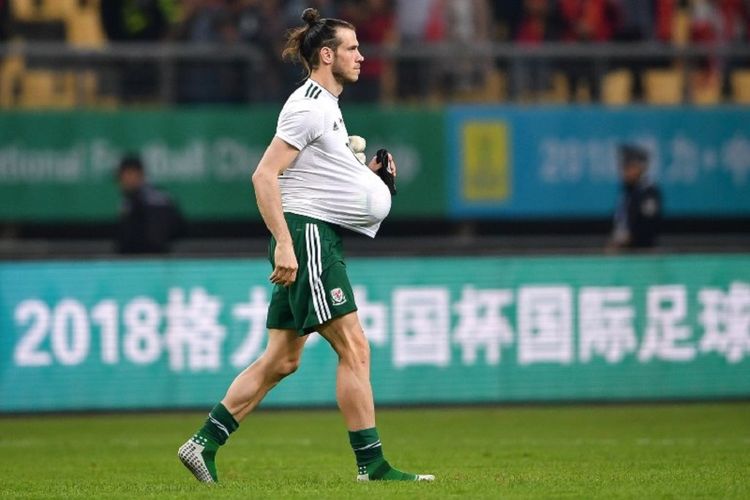 Gareth Bale membawa bola pertandingan timnas China vs Wales lantaran sukses mencetak hat-trick pada laga di Guangxi, Kamis (22/3/2018) tersebut. 