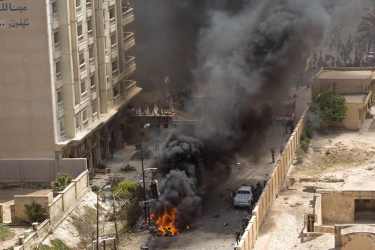Sebuah mobil terbakar di lokasi serangan bom di kota pelabuhan utara Alexandria, Mesir (24/3/2018). (AFP)