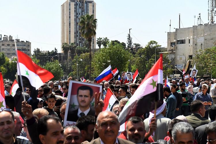 Sambil mengibarkan bendera nasional dan membawa foto Presiden Bashar al-Assad, rakyat Suriah berkumpul di lapangan Saadallah al-Jabiri, Aleppo, Sabtu (14/4/2018) untuk mengecam serangan AS dan sekutunya terhadap negeri itu. 