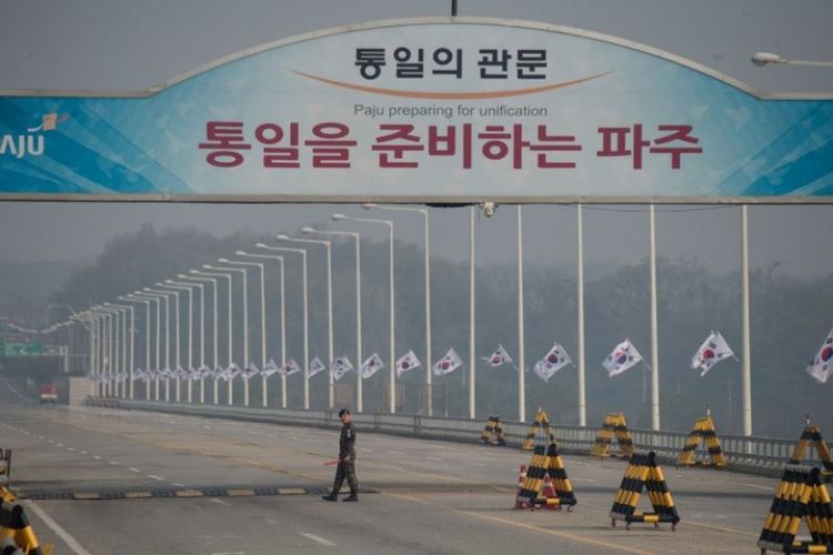 Seorang tentara Korea Selatan berjalan di jembatan Tongil,  sebelum pos pemeriksaan yang mengarah ke Zona Demiliterisasi dan desa gencatan senjata Panmunjom, di Paju, Jumat (27/4/2018). (AFP/Ed Jones)