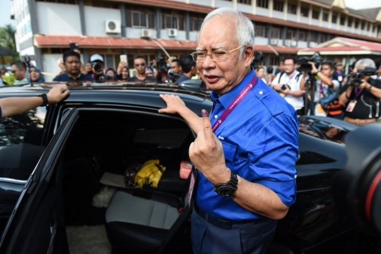 Perdana Menteri Malaysia Najib Razak menunjukkan jari yang terkena tinta, setelah memilih di tempat pemungutan suara di Pekan, Rabu (9/45/2018). (AFP/Mohd Rasfan)
