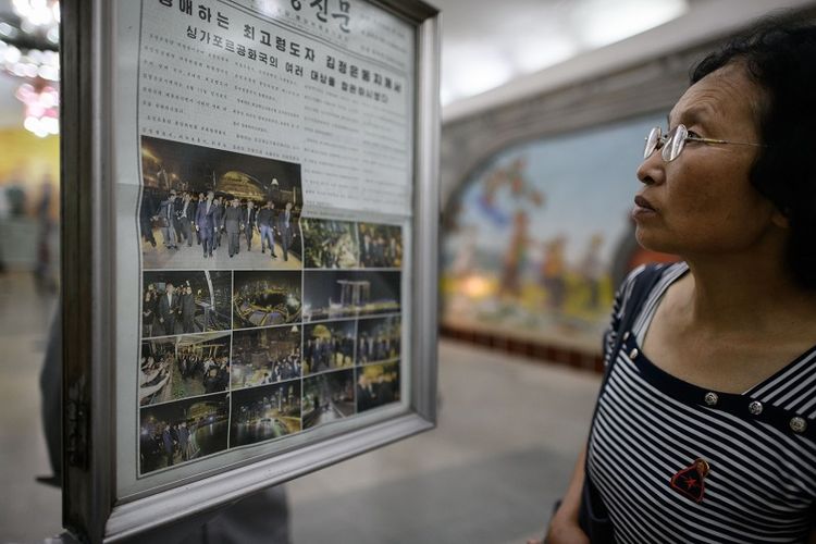 Seorang warga Korea Utaara membaca edisi terbaru harian Rodong Sinmun yang menampilkan sedert foto Kim Jong Un sedang berjalan-jalan di Singapura, Senin (11/6/2018). 
