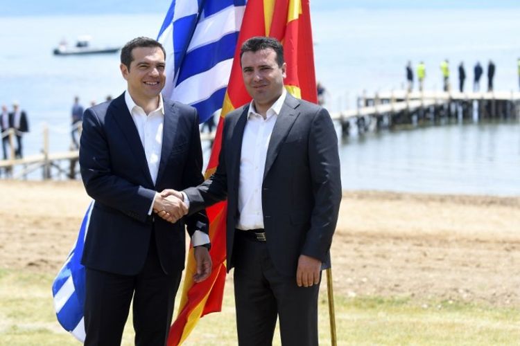 Perdana Menteri Macedonia Zoran Zaev (kanan) menyambut Perdana Menteri Yunani Alexis Tsipras (kiri) di tepi Danau Prespa dekat Otesevo Minggu (17/6/2018) dalam kesepakatan pergantian nama Macedonia menjadi Republik Macedonia Utara. (AFP/Maja Zlatevska)