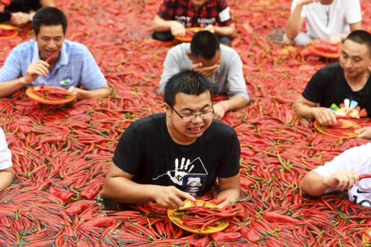 Kontestan mengambil bagian dalam kompetisi makan cabai di Ningxiang di provinsi Hunan, China, Minggu (8/7/2018). Pemenang lomba harus berhasil makan 50 cabai dalam satu menit. (AFP)
