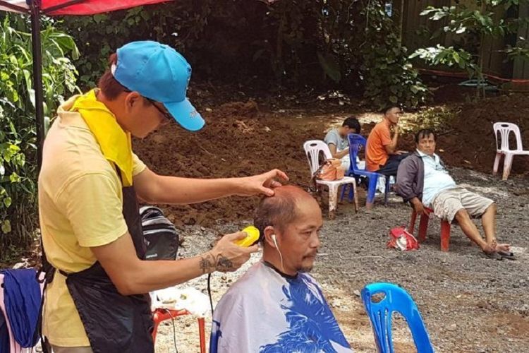 Seorang relawan mencukur rambut relawan lain dalam operasi penyelamatan 13 anggota tim sepak bola remaja yang terjebak di Goa Tham Luang, Thailand, sejak 23 Juni lalu.