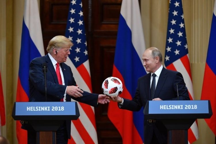 Presiden Rusia Vladimir Putin memberikan bola Piala Dunia 2018 ke Presiden Amerika Serikat Donald Trump pada konferensi pers bersama usai pertemuan di Istana Presiden di Helsinki, Finlandia, Senin (16/7/2018). (AFP/Yuri Kadobnov)