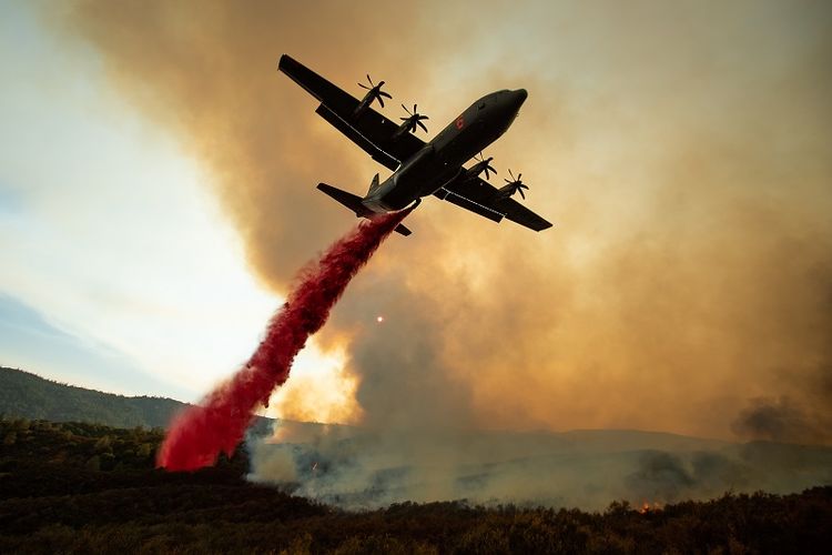 Sebuah pesawat tanker menyiramkan air ke arah lokasi kebakaran hutan di California, AS.