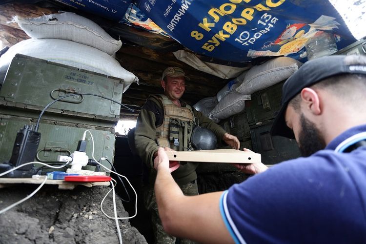 Aleksey Kachko, salah seorang pemilik kedai Pizza Veterano in Mariupol, Ukraina menyerahkan sekotak pizza kepada seorang tentara Ukraina yang bertugas di garis depan menghadapi pemberontak pro-Rusia di wilayah timur negeri itu. 