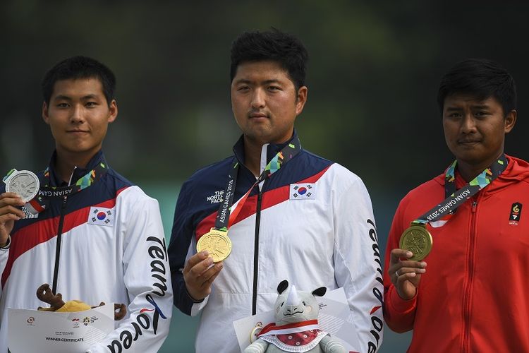 Dalam foto ini terlihat atlet panahan Korea Selatan Lee Woo-seok yang merah medali perak dan atlet Indonesia Ega Agata Salsabilla mengapit sang juara Kim Woo-jin dalam penyerahan medali nomor recurve individual putra di Asian Games Jakarta 2018.