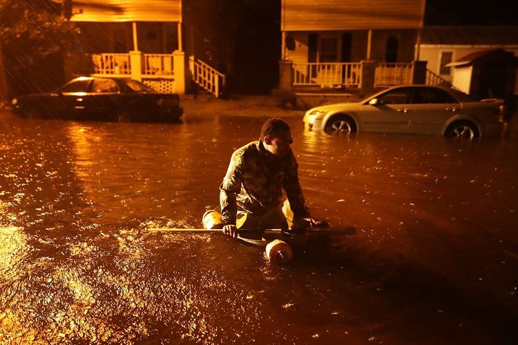 Seorang warga kota New Bern, Carolina Utara menaiki perahu darurat setelah air di Sungai Neuse yang meluap akibat badai Florence, Kamus (13/9/2018) malam. 