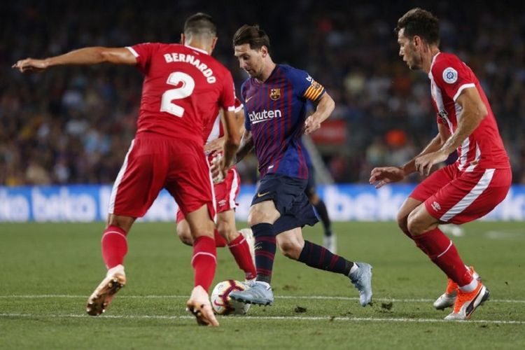 Lionel Messi mencoba melewati penjagaan dua pemain lawan saat Barcelona vs Girona dalam pertandingan lanjutan La Liga Spanyol di Camp Nou, 23 September 2018. 