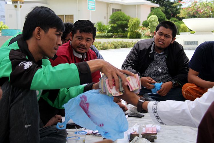sejumlah driver ojek online sedang menghitung sumbangan yang digalang untuk korban gempa dan tsunami Palu di halaman Masjid Raya Baiturrahman Kota Banda Aceh,  Senin (08/10/18)