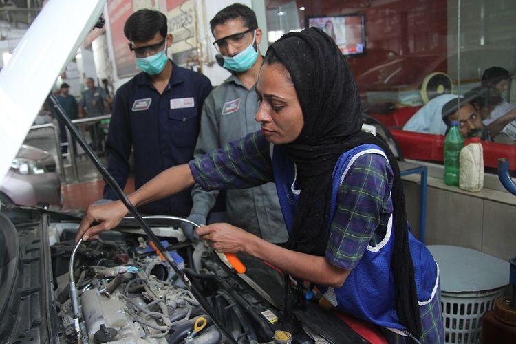 Dalam foto yang diambil pada 1 September 2018 ini, terlihat Uzma Nawaz (24) tengah memeriksa mesin sebuah mobil di sebuah bengkel di kota Multan, Pakistan.