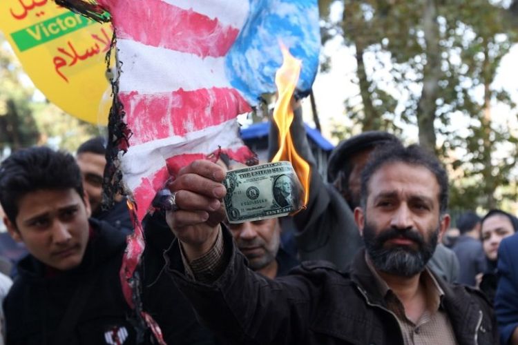 Jelang penerapan sanksi Amerika Serikat, pengunjuk rasa di Iran membakar uang kertas dollar selama demonstrasi di luar gedung bekas kedutaan besar AS di Teheran, Minggu (4/11/2018). (AFP/Atta Kenare)