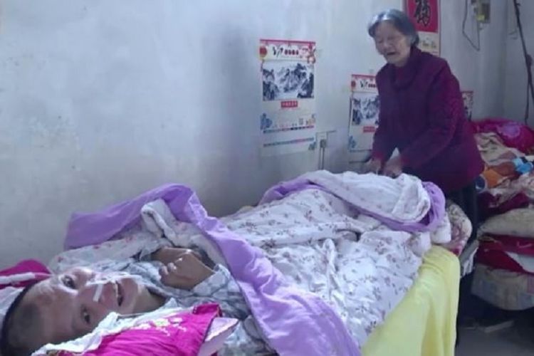 Wang Shubao (48) tersadar dari kondisi koma yang sudah dilaluinya selama 12 tahun. Di ujung tempat tidur terlihat Wei Mingying (75), sang ibu yang merawatnya selama ini. 