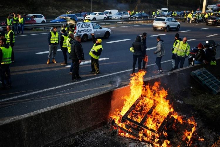 Massa memblokir jalan di Caen, Normandia, yang tergabung dalam gerakan rompi kuning (Gilets Jaunes dalam bahasa Perancis) untuk memprotes harga bahan bakar minyak yang tinggi pada Sabtu (17/11/2018). (AFP/Charly Triballeau) 