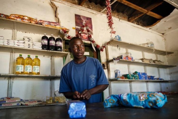 Solomon Chakauya, menunggu pelanggan di toko kelontongnya, di distrik Chinamhora, Zimbabwe. Foto ini diambil pada 10 Desember 2018. (AFP/JEKESAI NJIKIZANA)