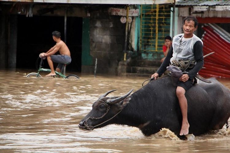 Masyarakat melewati jalan yang banjir di kota Baao di provinsi Camarines Sur pada Minggu (30/12/2018), usai badai Usman melanda wilayah di Filipina pada Sabtu (29/12/2018). (AFP/Simvale Sayat)