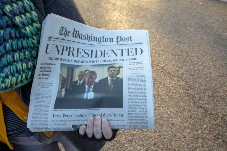 Relawan mendistribusikan The Washington Post palsu, yang menyebut Donald Trump mengundurkan diri dari jabatan Presiden Amerika Serikat. Foto ini diambil pada Rabu (16/1/2019). (AFP/TASOS KATOPODIS)