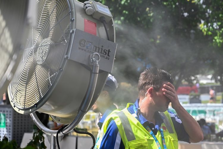 Seorang pria mendinginkan diri di depan kipas angin yang menyemburkan air untuk sedikit mengurangi rasa panas di luar stadion yang menggelar turnamen Australia Terbuka pada Januari lalu. Badan Meteorologi Australia mencatat, bulan lalu menjadi Januari terpanas sejak 1910. 