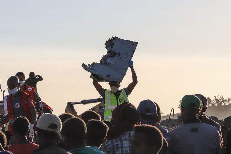 Seorang petugas membawa sebuah potongan pesawat milik Ethiopian Airlines di dekat kota Bishoftu,  60 kilometer sebelah tenggara  ibu kota Addis Ababa. Tragedi ini menewaskan 157 orang penumpang dan awak pesawat.