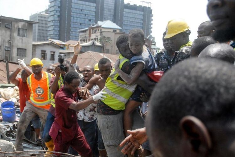 petugas  menyelamatkan seorang anak di lokasi sebuah bangunan yang runtuh di Lagos, Nigeria, Rabu (13/3/2019). (AFP/SEGUN OGUNFEYITIMI)