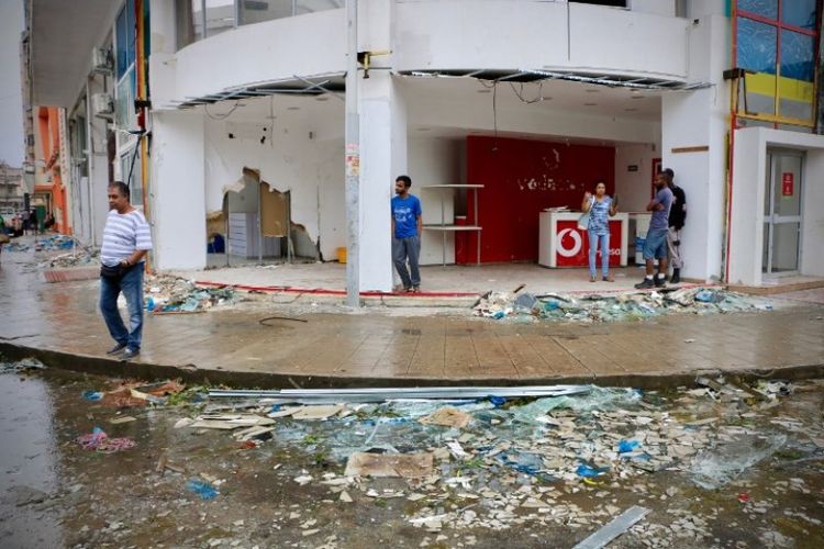 Penduduk dan penjaga toko terlihat berada di sebuah kawasan pertokoan setelah topan Idai melanda Beira, Mozambik, pada Minggu (17/3/2019). (AFP/ADRIEN BARBIER)