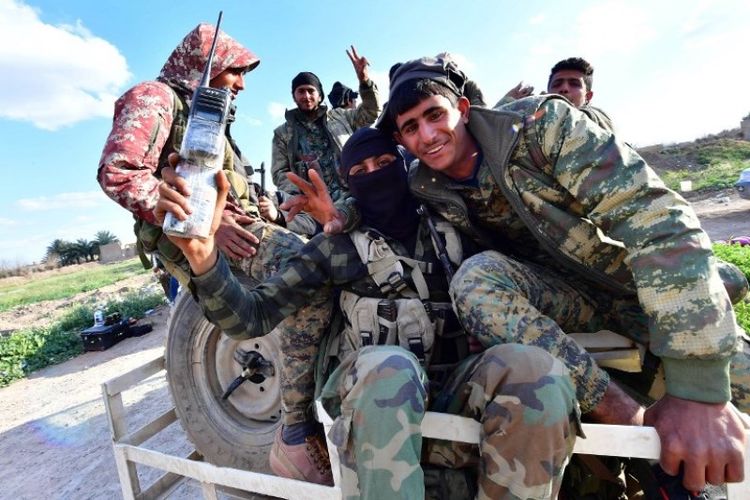 Tentara Pasukan Demokrat Suriah (SDF) mengacungkan jari berbentuk V untuk tanda kemenangan ketika mereka kembali dari garis depan pertempuran melawan ISIS di desa Baghouz, Suriah Deir Ezzor, Suriah, Selasa (19/3/2019). (AFP/CACACE GIUSEPPE)