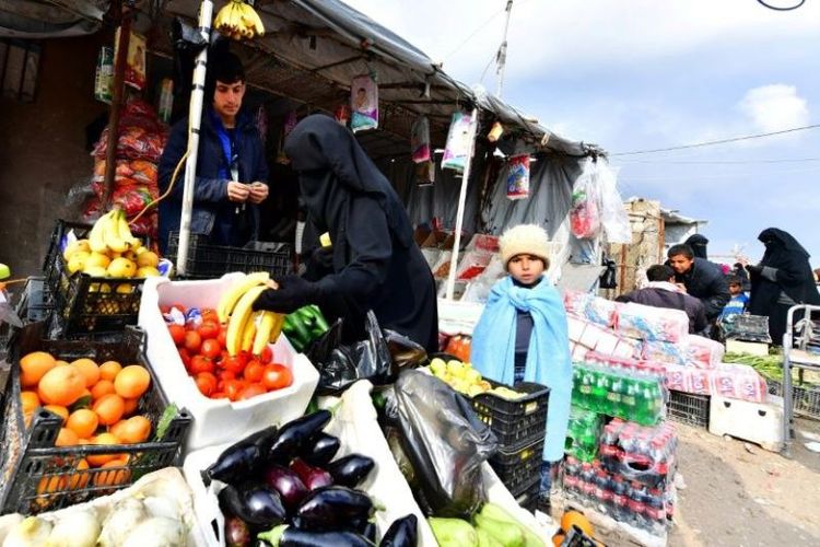 Pengungsi membeli sayuran dan buah-buahan di pasar kamp pengungsian Al-Hol, Suriah, yang saat ini dipenuhi dengan lebih dari 70.000 orang. (AFP/CACACE GIUSEPPE)