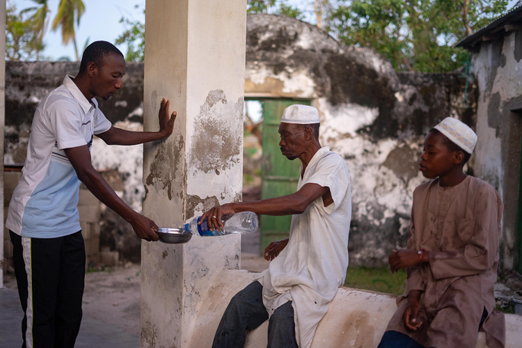 Pria di Pulau Ibo, Mozambik, berbagi sebotol air untuk berbuka puasa sebelum sholat magrib pada bulan suci Ramadhan, Senin (13/5/2019). (AFP/Bibi Zinyange)