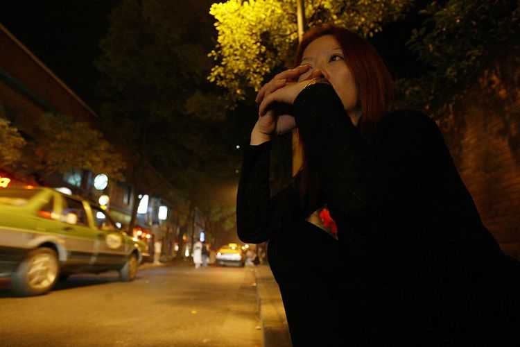 Seorang pekerja seks komersia duduk dalam kegelapan saat  menunggu pelanggan di dekat sebuah distrik bar populer di Shanghai, China, pada 7 Juni 2003. (Reuters/Claro Cortes)