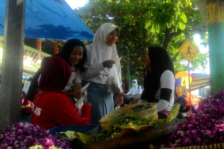 Vania Uly dan Nafiah Rahma membagikan nasi bungkus dan susu hangat ke pedagang bunga tabur di Pasar Wates, Kulon Progo, Rabu (2/5/2018)