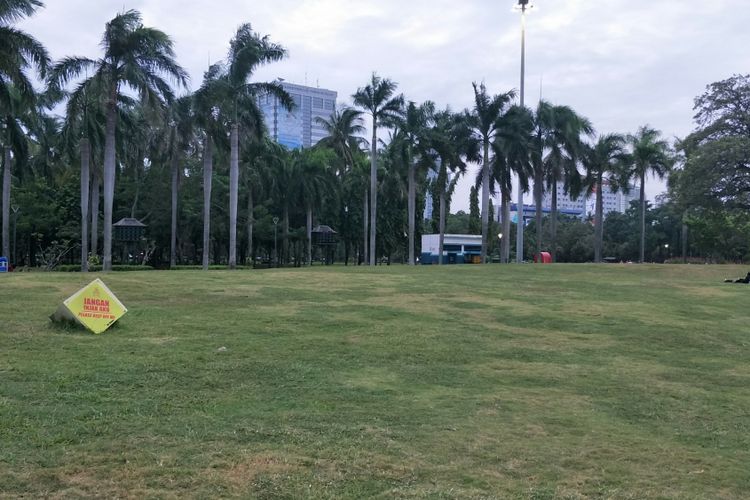 Pagar taman atau pagar pembatas rumput di kawasan Monas, Jakarta Pusat, telah dicopot. Warga pun tampak duduk di atas rumput. Namun, tanda peringatan Jangan Injak Aku yang dipasang di area rumput masih terpasang. Foto diambil Kamis (11/12/2018).