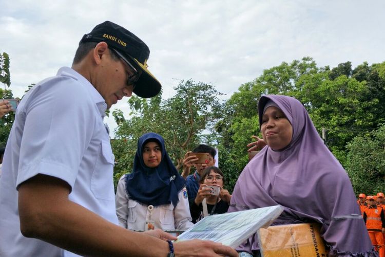 Wakil Gubernur DKI Jakarta Sandiaga Uno memberikan santunan BPJS Ketenagakerjaan kepada keluarga petugas PPSU yang telah meninggal saat memimpin apel petugas penanganan prasarana dan sarana umum (PPSU) serta penyedia jasa lainnya perorangan (PJLP) se-Kecamatan Cipayung di halaman Kantor Camat Cipayung, Jakarta Timur, Rabu (24/1/2018).