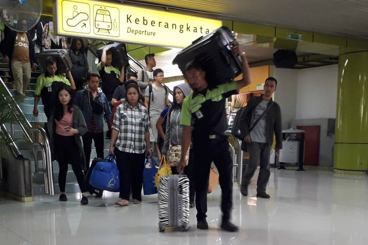 Seorang porter tengah membawa koper milik penumpang di Stasiun Gambir, Jakarta Pusat, Sabtu (9/6/2018).