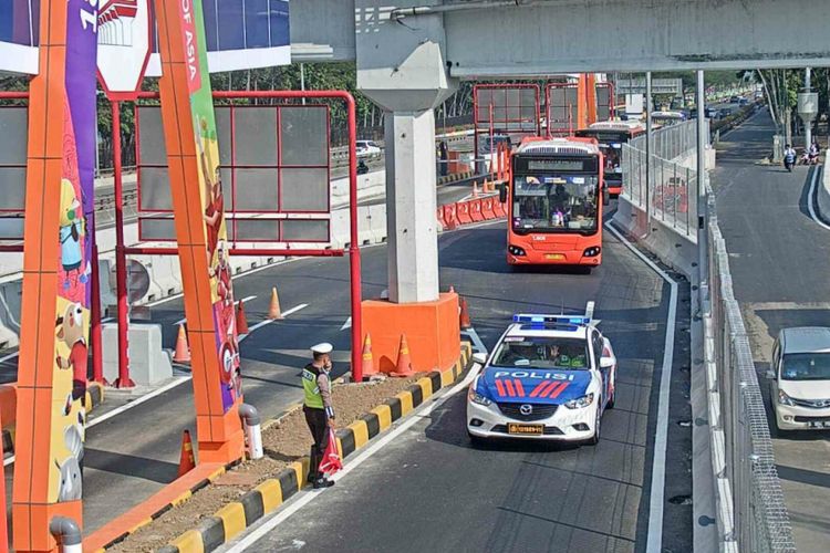 Petugas melakukan pengawalan bus atlet di jalan tol.