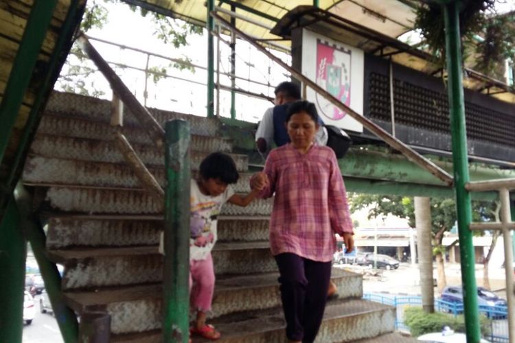 Seorang ibu dan anak berhati-hati saat turun dari tangga JPO di Jalan Jenderal Sudirman, Pekanbaru, Riau, yang kondisinya sudah rusak, Rabu (19/9/2018). Seorang warga bernama Edi Ibrahim (57) pernah jatuh dari JPO ini hingga akhirnya meninggal dunia sepekan lalu.