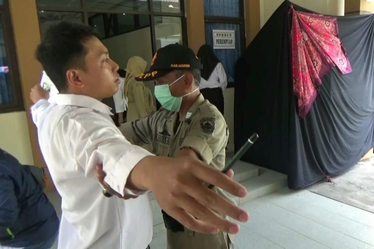 Tim Panitia Seleksi Daerah (panselda) penerimaan CPNS Kabupaten Madiun saat memeriksa badan peserta tes yang hendak masuk di ruang ujian.