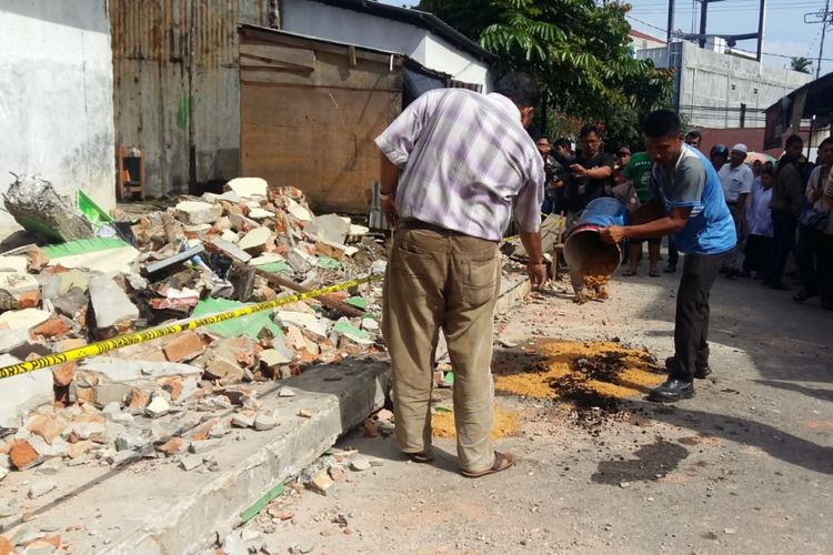 Warga menimbun darah korban yang tertimpa tembok sekolah dasar di Jalan Tengku Bey, Kelurahan Simpang Tiga, Kecamatan Bukit Raya, Pekanbaru, Riau, Rabu (14/11/2018).