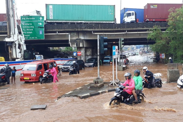 Tampak Banjir setinggi lutut orang dewasa menggenang di kolong Tol JORR Jalan KH.Noer Ali, Bekasi Barat, Kota Bekasi, Senin (26/11/2018).