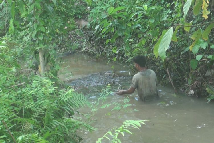 Seorang warga tampak sedang membersihkan air sungai dari limbah minyak hasil tumpahan pipa milik PT Pertamina EP Asset 2 Prabumulih yang bocor minggu malam (2/12/2018) lalu.