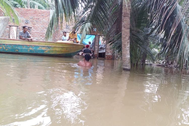Seorang pria bernama Jefrizal (38) mengarungi banjir untuk menuju rumahnya yang banjir di Desa Buluh Cina, Kecamatan Siak Hulu, Kabupaten Kampar, Riau, Senin (17/12/2018).