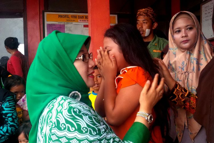 Anggota DPR RI Reni Marlinawati (kiri) memeluk seorang anak penyintas bencana longsor Dusun Cimapag, Desa Sirnaresmi, Kecamatan Cisolok, Sukabumi, Jawa Barat, Kamis (10/1/2019).